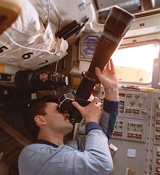 Mir-22 flight engineer Alexander Kaleri uses a long lens to take photos from the aft flight deck windows of the STS-79 orbiter Atlantis. 