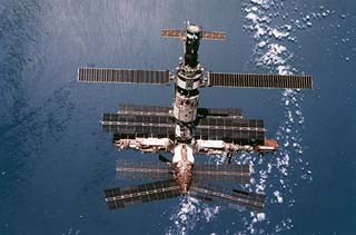 Full view of the Mir space station against a cloudy Earth.