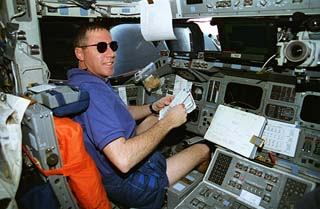 Mission commander Michael Baker (wearing sunglasses) is photographed at his station on the forward flight deck. 