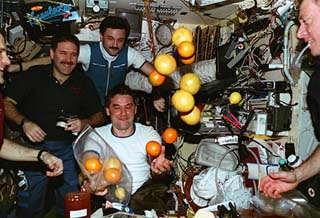 The Mir-22 and STS-81 crew watch the fruit fly free in the Base Block module. 