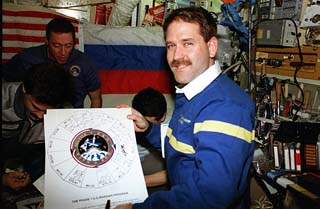 Mission specialist John Grunsfeld holds up the Shuttle/Mir program photo to show the crew signatures.