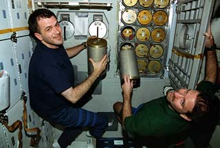 STS-81 mission specialist Jeff Wisoff (left) and John Grunsfeld perform a Lioh canister changeout in the Atlantis's middeck.