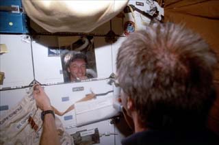 View of STS-86 mission specialist Michael Foale using a mirror on the Atlantis's middeck locker to shave. 