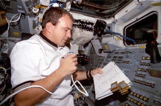 STS-86 pilot Michael Bloomfield reviews a checklist as he communicates via radio while at the commander's station on the Atlantis's forward flight deck. 