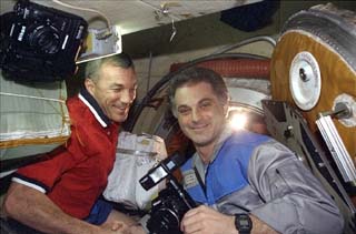 Commander Terrence Wilcutt waiting at the airlock greets Mission Specialist David Wolf.