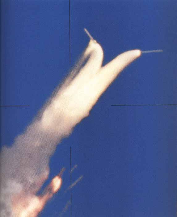 At right, the boosters diverge farther; the External Tank wreckage is obscured by smoke and vapor. The Orbiter engines still firing, is visible at bottom center.